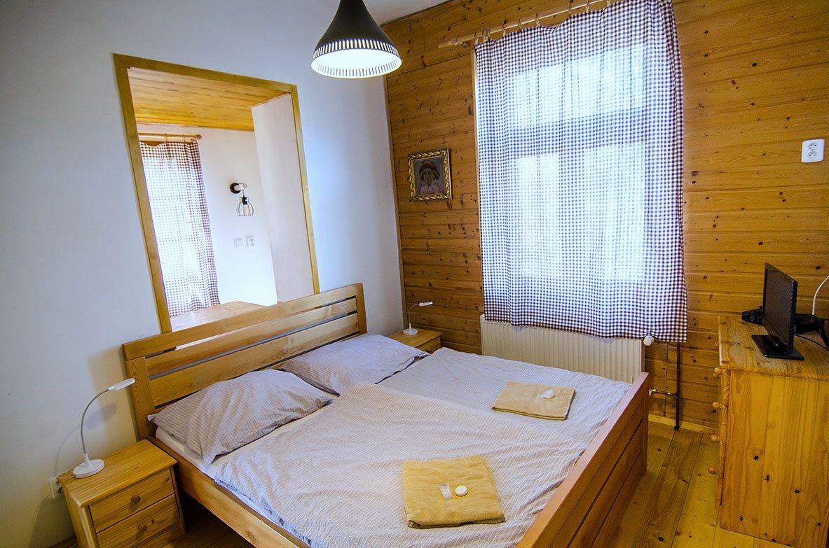 Pokoj č. 2 — manželská postel pod dřevěným stropem